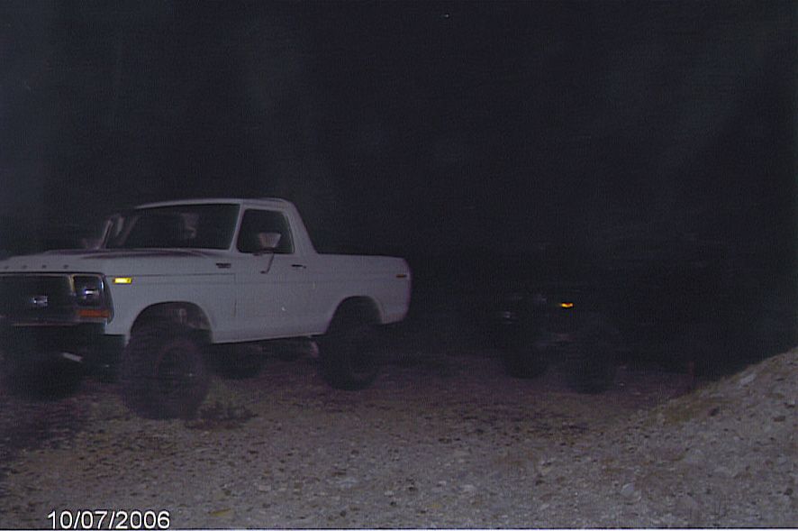 White lifted Ford truck parked on a dim graded slope at dusk