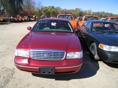 1991 Ford LTD Crown Victoria - Two Ford Crown Victorias are parked outdoors. One is red, the other is dark green.