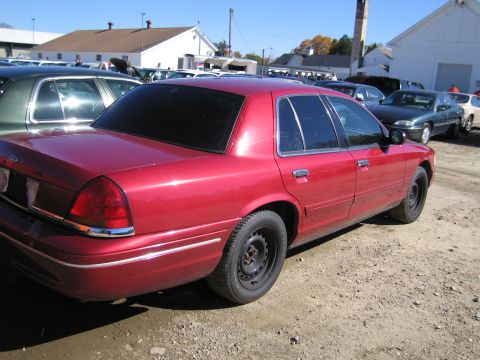 1991 Ford LTD Crown Victoria - A red sedan is parked in a lot with other vehicles under a clear sky.
