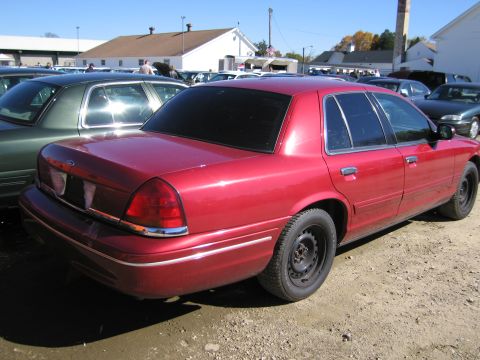 1991 Ford LTD Crown Victoria - A red sedan is parked in a lot with other vehicles. The car appears to be a later model Crown Victoria, not a 1991.