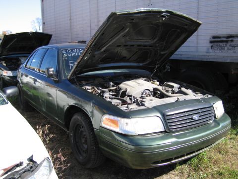 1991 Ford LTD Crown Victoria - A green 1991 Ford Crown Victoria LTD is parked with its hood open, revealing the engine compartment. Another vehicle is partially visible t…