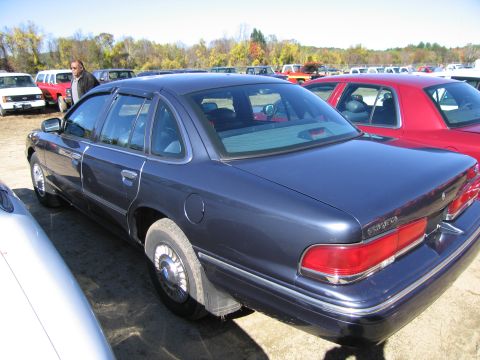 1991 Ford LTD Crown Victoria - A dark blue sedan is parked in an outdoor lot with several other vehicles visible.