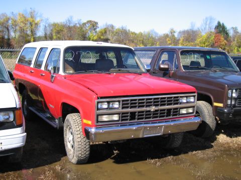 1991 Ford LTD Crown Victoria - This red and white Chevrolet K5 Blazer SUV is parked on muddy ground next to other vehicles.