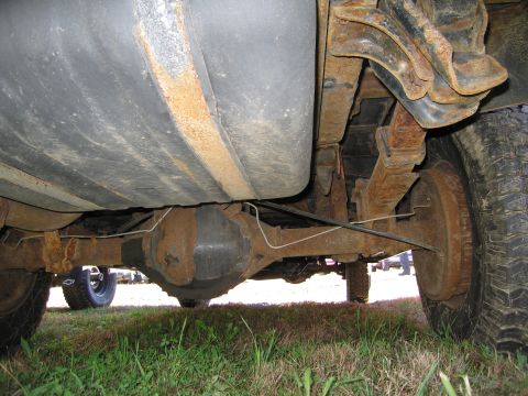 1991 Ford LTD Crown Victoria - The underside of a vehicle reveals significant rust on its components, including the fuel tank and rear axle.