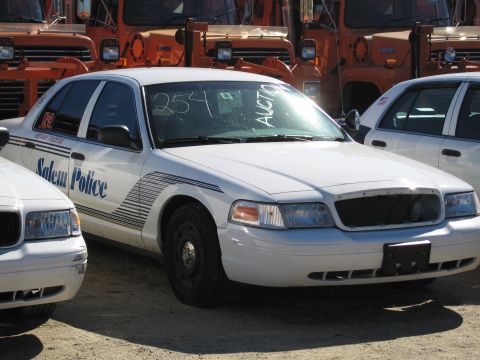 1991 Ford LTD Crown Victoria - White police car with "Salem Police" text on door, parked next to another white car, with snow plows in the background.