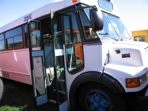1991 Ford LTD Crown Victoria - Front view of a white Thomas bus with its doors open, revealing the interior.