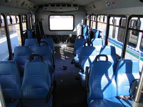 1991 Ford LTD Crown Victoria - Interior view of a bus showing rows of blue seats and luggage stowed.
