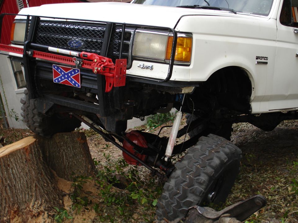 White Ford Bronco front corner on a stump with Hi-Lift jack and red front differential