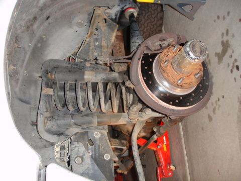 1996 Ford Bronco - Close-up view of a vehicle's front suspension system, highlighting the coil spring and brake rotor. The Supermotors.net logo is visible in…