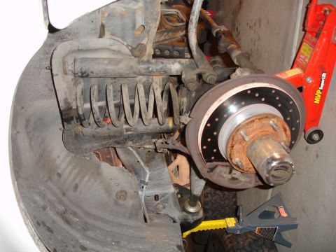 1996 Ford Bronco - Close-up of a vehicle's front suspension and brake components during a lift installation.