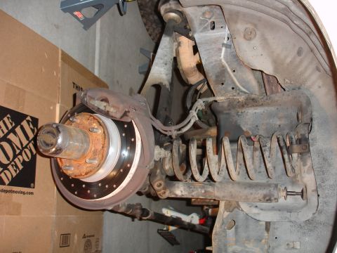 1996 Ford Bronco - Close-up view of a vehicle's front suspension and brake components, likely during a lift installation.