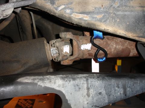 1996 Ford Bronco - Close-up view of a vehicle's driveshaft and exhaust pipe with a strap attached.