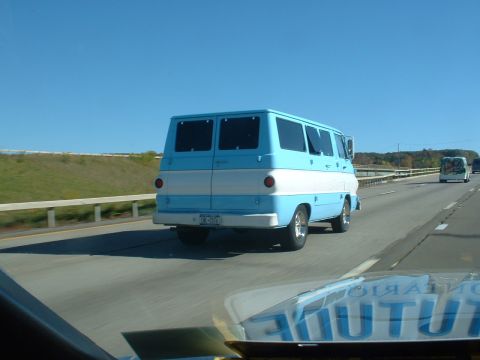 1978 Ford Mustang II - A blue and white van travels down the highway on a clear day.