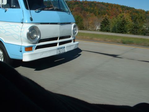1978 Ford Mustang II - A blue and white van with flame decals drives down the highway on a sunny day.