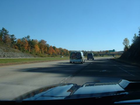 1978 Ford Mustang II - Driving on the highway with two vans in front, one decorated with art.