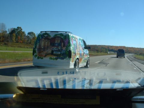 1978 Ford Mustang II - A van with a detailed mural is driving on the highway under a clear blue sky.