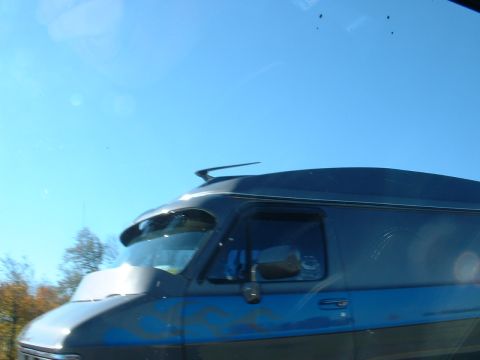 1978 Ford Mustang II - A dark blue van with flame decals is captured from the side under a clear blue sky.