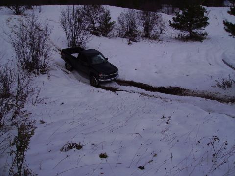 2000 Chevrolet Tahoe - A black pickup truck navigates a challenging snowy terrain, leaving tracks in the mud.