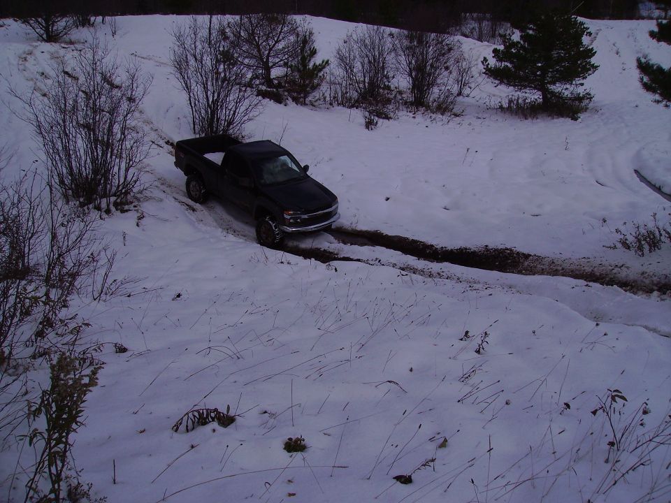 Black pickup truck driving on a snowy, muddy track. Looks like a 2003 model