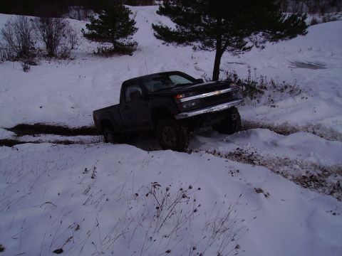 2000 Chevrolet Tahoe - A black pickup truck navigates a snowy, muddy terrain, with its front end angled towards the viewer.