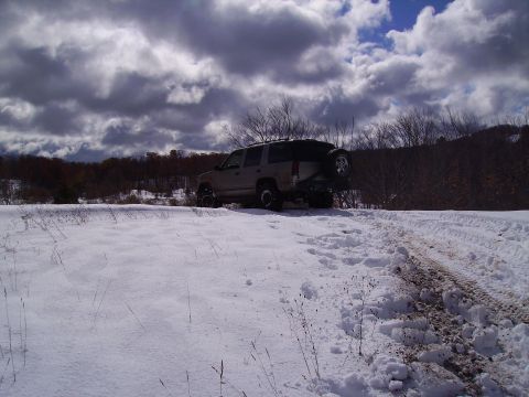 2000 Chevrolet Tahoe - A tan 2000 Chevrolet Tahoe navigates a snowy path, its spare tire mounted on the rear.