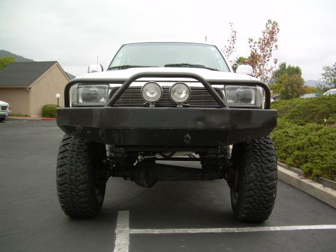 1993 Toyota 4Runner - Front view of a white SUV with a heavy-duty bumper and off-road tires, parked in a lot.