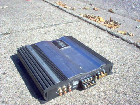1994 Ford Probe - Car amplifier with visible text and connectors sits on a concrete surface.