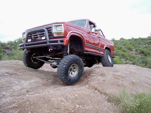 1991 Ford Bronco - This lifted 1980s Ford Bronco navigates a dirt incline, its off-road capabilities and suspension.