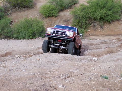 1991 Ford Bronco - This lifted truck navigates a challenging dirt path, its off-road capabilities.