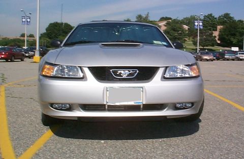 2000 Ford Mustang - A silver Ford Mustang is parked in a lot, facing the camera directly.