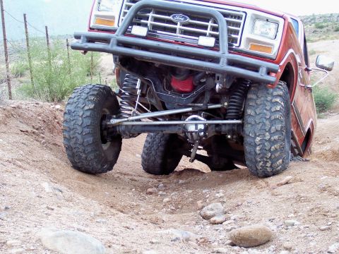 1991 Ford Bronco - Modified red Ford Bronco navigating a challenging off-road course.