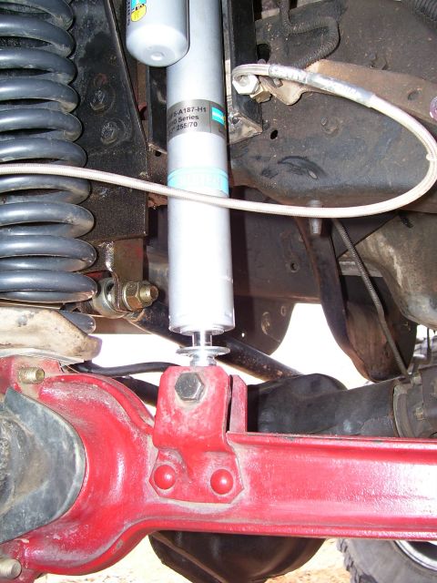 1991 Ford Bronco - Close-up of the suspension system, a red axle and a silver Bilstein shock absorber with visible part numbers.
