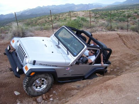 1991 Ford Bronco - This Jeep Wrangler Rubicon is navigating a challenging off-road trail in a desert landscape.