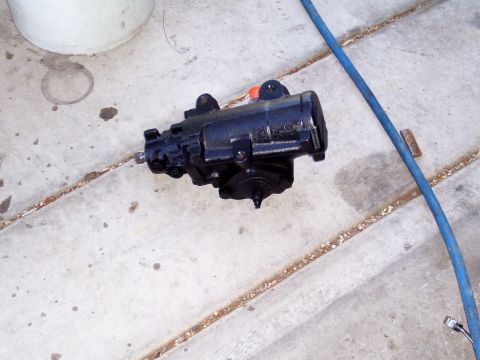 1991 Ford Bronco - A black steering gear box sits on a concrete surface next to a blue hose.
