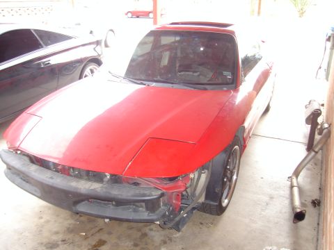 1997 Ford Probe - A red 1997 Ford Probe is seen from the front-three-quarter view, with its pop-up headlights visible and the front bumper removed.