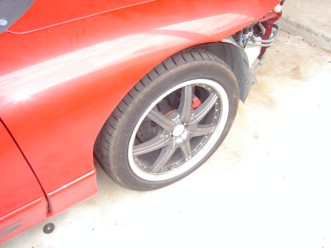 1997 Ford Probe - Close-up of a red car's fender and a custom wheel with a visible red brake caliper. The front bumper area appears damaged.