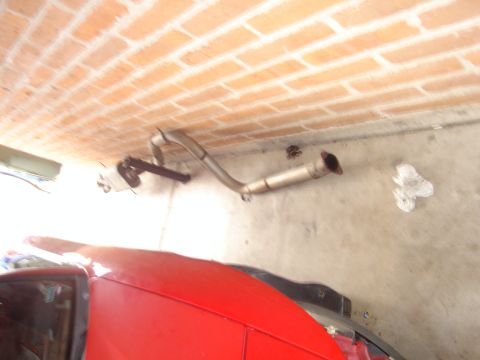 1997 Ford Probe - Exhaust pipe is mounted on the wall above a red car.