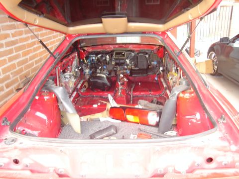 1997 Ford Probe - The interior of a red car has been completely disassembled, revealing exposed wiring and structural components.