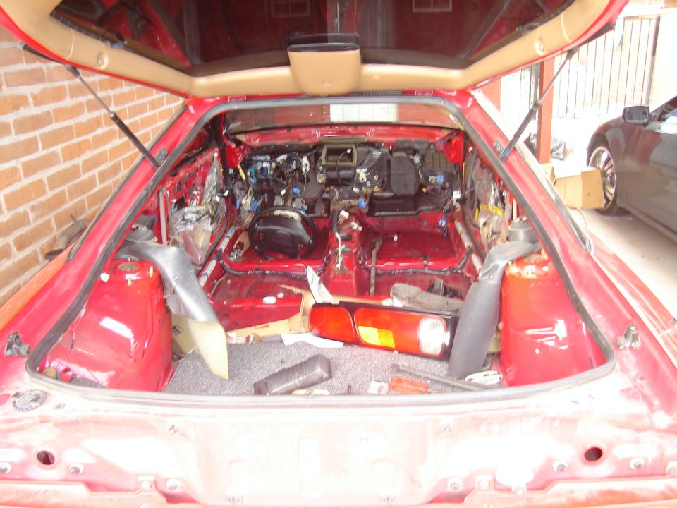 red car interior stripped down to the metal, showing wiring and components