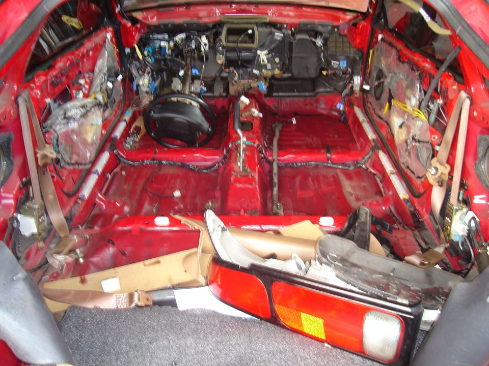 Red 1997 Ford Probe interior stripped bare, showing exposed wiring and body panels