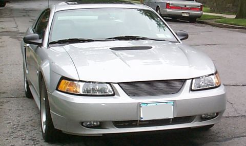 2000 Ford Mustang - A silver 2000 Ford Mustang is parked on a street, with another vehicle visible in the background.