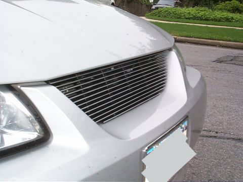 2000 Ford Mustang - Close-up of a white car's front end, highlighting a custom horizontal bar grille and headlight assembly.