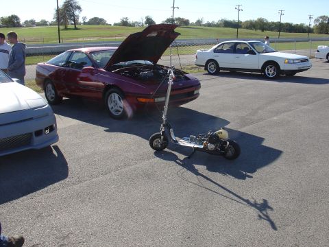 1993 Ford Probe - A red 1993 Ford Probe sits with its hood open, a scooter in front, and another car nearby.