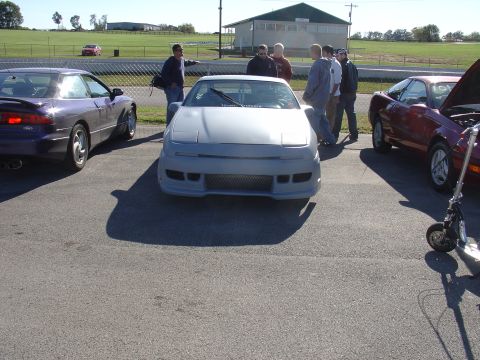 1993 Ford Probe - Several Ford Probes are gathered at an outdoor event, with one undergoing inspection.