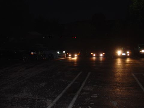 1993 Ford Probe - Multiple vehicles are parked in a lot at night with their headlights illuminated.