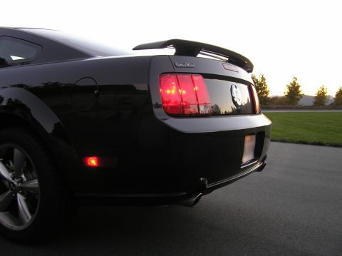 2007 Ford Mustang - The rear of a black Ford Mustang is shown parked on an asphalt driveway at dusk.