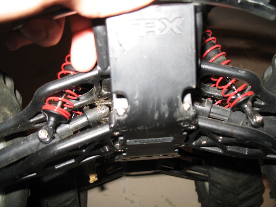 Underside of a Traxxas RC vehicle showing skid plate and red springs