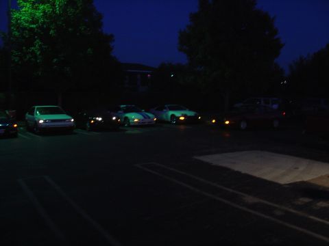 1993 Ford Probe - Multiple vehicles are parked in a dimly lit lot after dark.