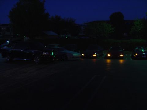 1993 Ford Probe - A group of cars are parked in a lot at night, with their headlights illuminating the ground.