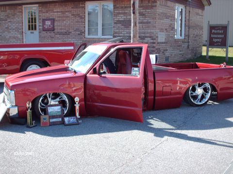 1995 Ford Probe - A customized red pickup truck is displayed with its doors open, trophies and awards at an outdoor car show.